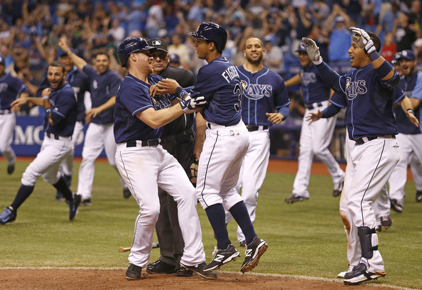  Logan Forsythe (L) and Yunel Escobar (R) come in to celebrate with Cole Figueroa #35 of the Tampa Bay Rays after Figueroa scored off a one-run game-winning fielder's choice by the Rays' Desmond Jennings to end the 15th inning of a game against the Boston Red Sox on May 24, 2014 at Tropicana Field in St. Petersburg, Florida. 