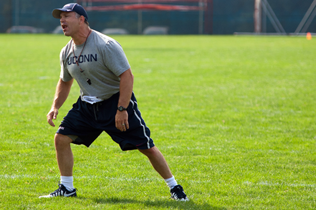 UConn Strength and Conditioning Coordinator Matt Balis leads the team through stretching drills before practice number five on August 6, 2014.